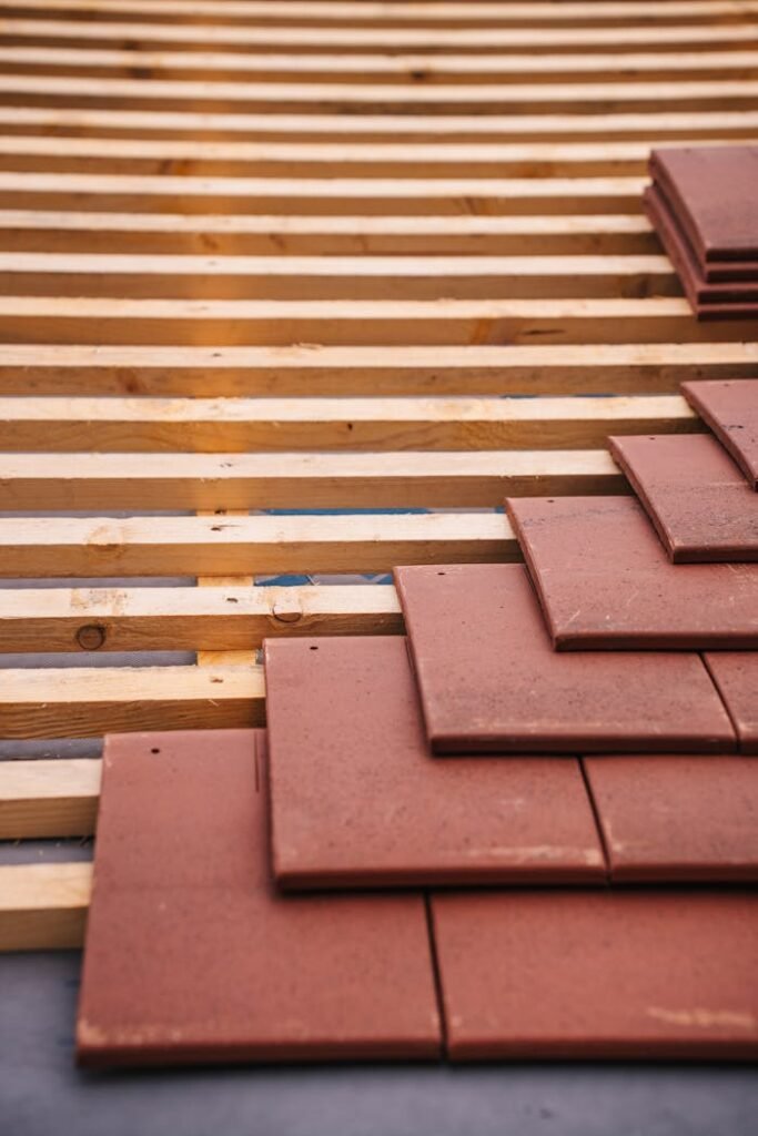 pexels-photo-31763538 Red roofing tiles and wooden framework in progress on a building roof.