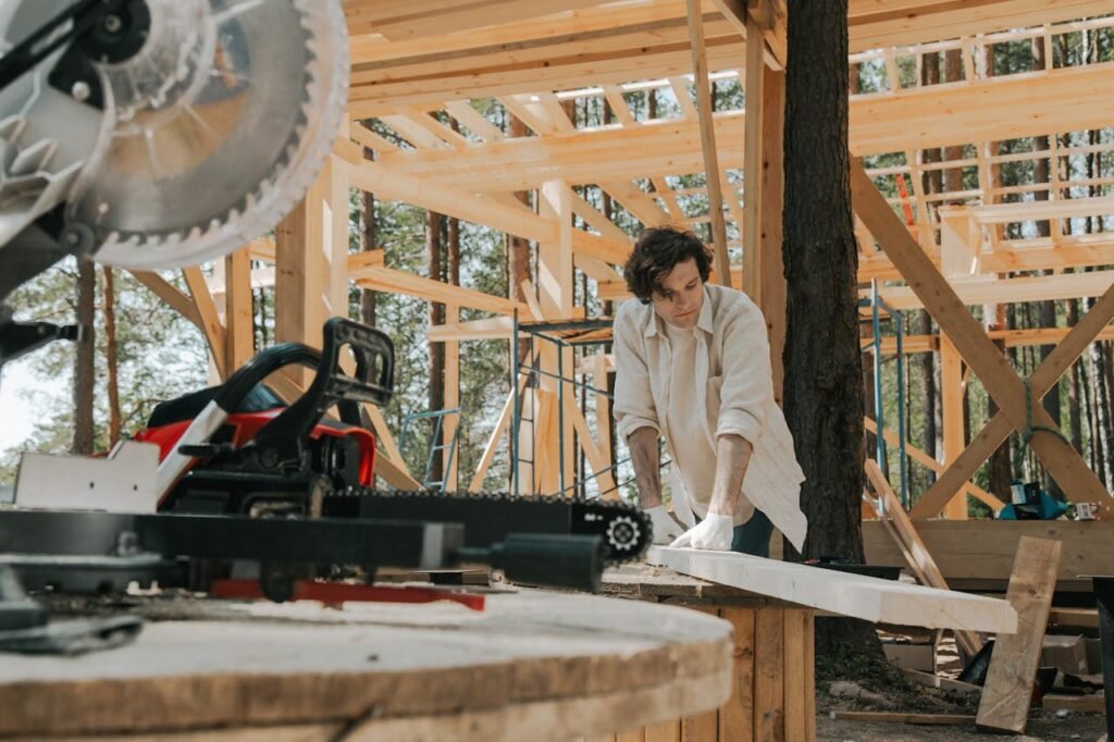 pexels-photo-8817847 A focused carpenter working with tools at a wooden construction site outdoors.