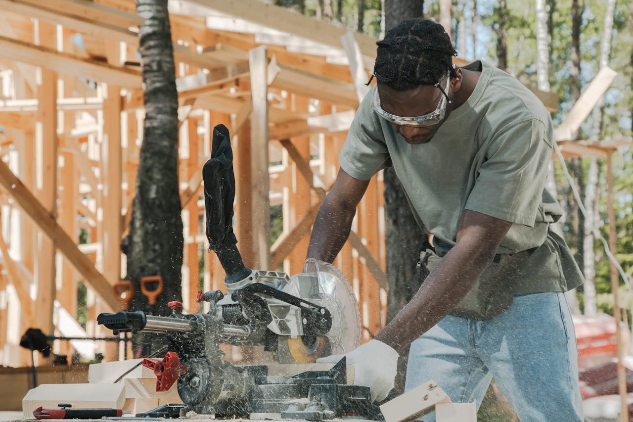 why-choose-us-01 A carpenter using a circular saw at an outdoor construction site.