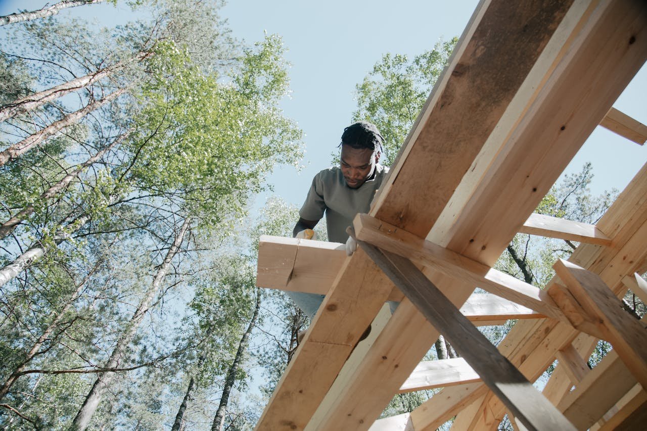 why-choose-us-02 Black male carpenter working on a wooden frame outdoors, showcasing detailed craftsmanship.